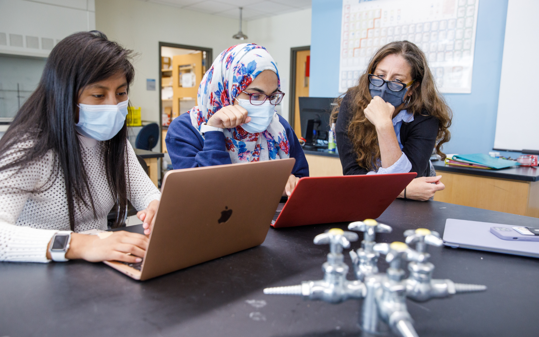 在一个科学实验室里，教授和两个学生正在审阅电脑屏幕上的信息