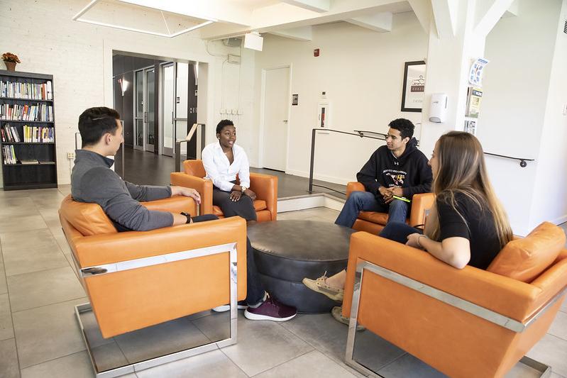 三名学生和一名职业顾问坐在就业中心的大厅里，坐在橙色的椅子上微笑
